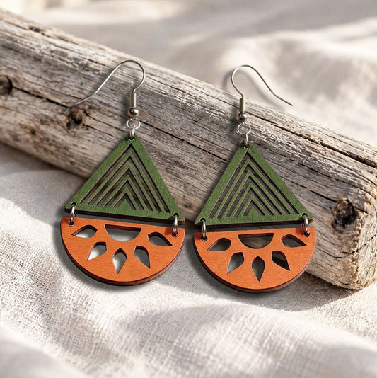 Orange and green Open Sea plywood earrings made in Finland, photographed on a vintage book in natural sunlight