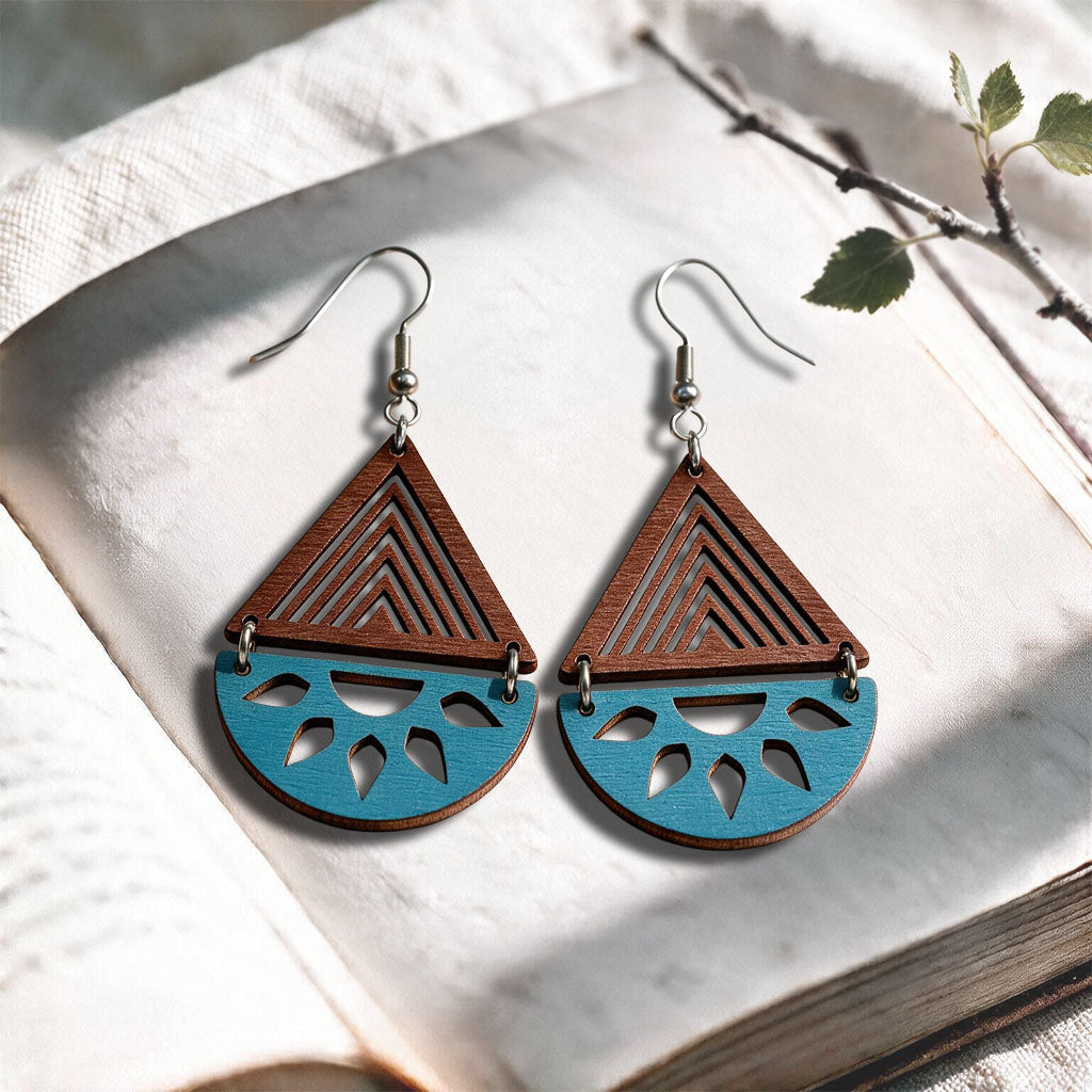 Walnut and blue turquoise Open Sea plywood earrings made in Finland, photographed on a vintage book in natural sunlight