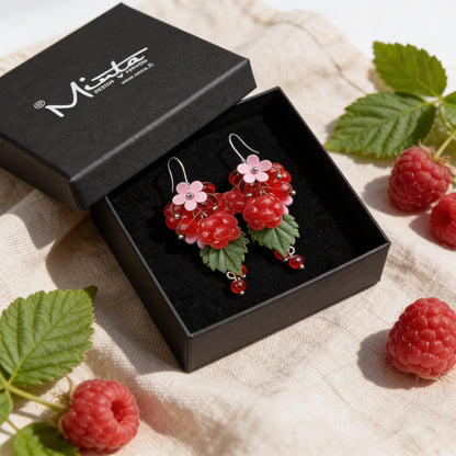 Raspberry Garden Earrings presented in a gift box, surrounded by natural linen fabric, fresh raspberries, and raspberry leaves. Handmade in Finland by byMinta.