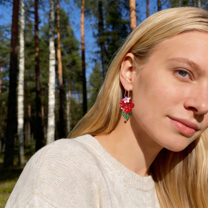 Blonde woman wearing Raspberry Garden Earrings in a sunlit Nordic forest. Handmade earrings inspired by the sweet glow of ripe garden raspberries.