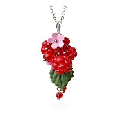 Handmade berry necklace featuring sculpted raspberries, translucent red glass berries, green leaves and delicate pink flowers. Botanical statement jewelry on a fine chain against a clean white background, handcrafted in Finland.