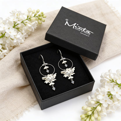 White Lilac Hoop Earrings presented in a gift box, surrounded by natural linen fabric and fresh white lilac blossoms. Handmade in Finland by byMinta.