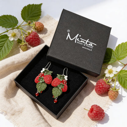 Wild Raspberry Earrings presented in a gift box, surrounded by natural linen fabric, fresh raspberries, raspberry leaves, and blossoms. Handmade in Finland by byMinta.