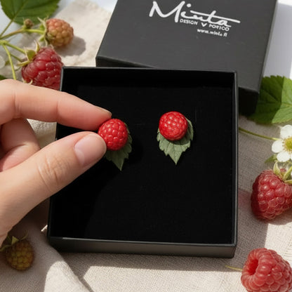 Hand holding handmade Wild Raspberry stud earrings in a gift box, showing the small size of the polymer clay berry jewelry. Nordic nature inspired earrings handcrafted in Finland by byMinta.