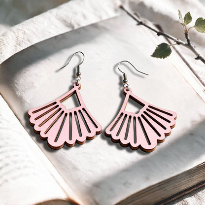 Babypink Fan plywood earrings made in Finland, photographed on a vintage book in natural sunlightYellow Fan plywood earrings made in Finland, photographed on a vintage book in natural sunlight