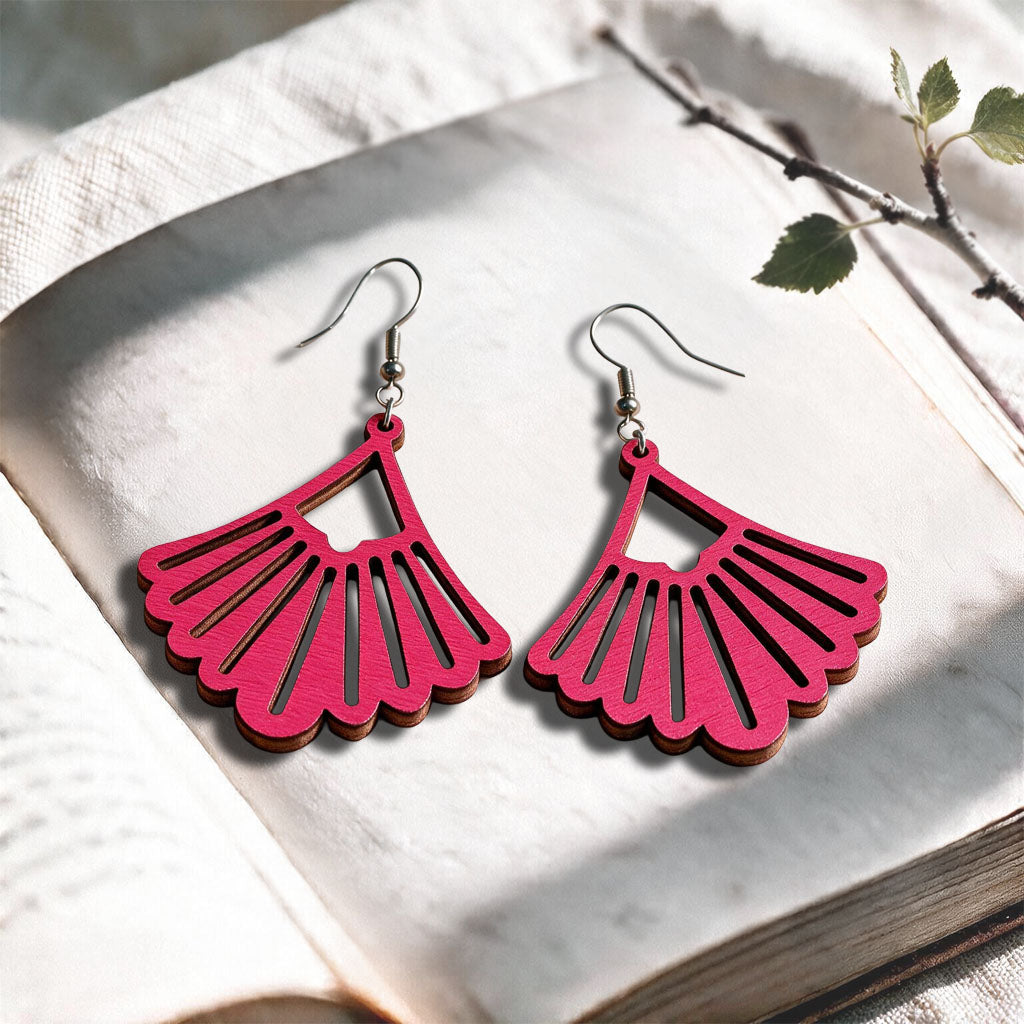 Raspberry Fan plywood earrings made in Finland, photographed on a vintage book in natural sunlight