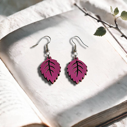 Heather Mini Birch plywood earrings made in Finland, photographed on a vintage book in natural sunlight