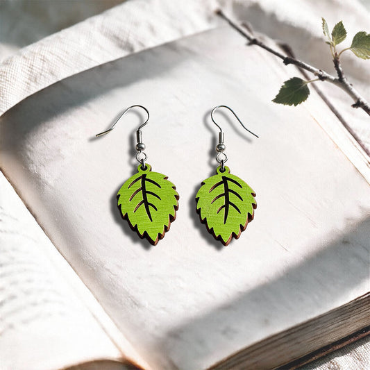 Lime Mini Birch plywood earrings made in Finland, photographed on a vintage book in natural sunlight