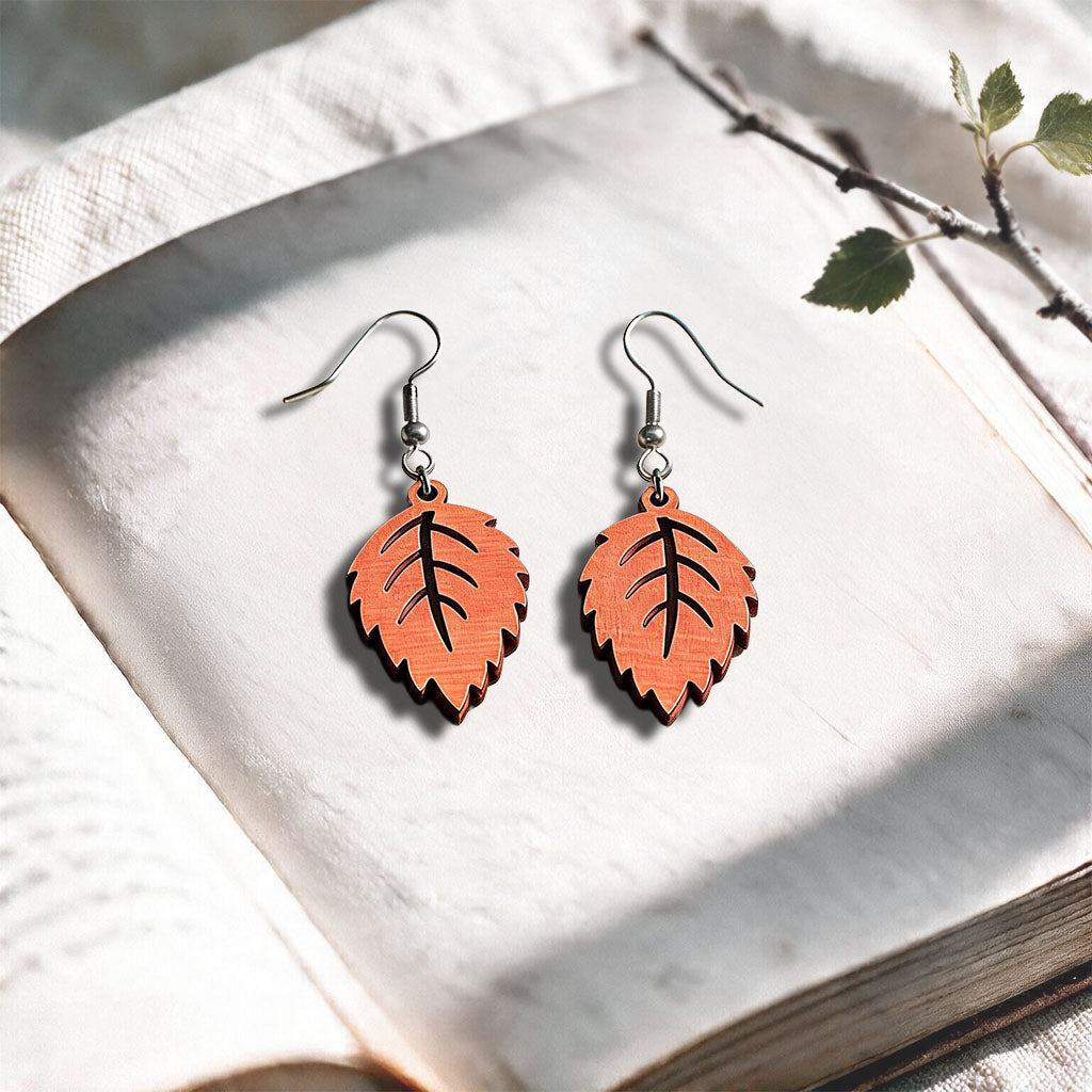 Papaya Mini Birch plywood earrings made in Finland, photographed on a vintage book in natural sunlight