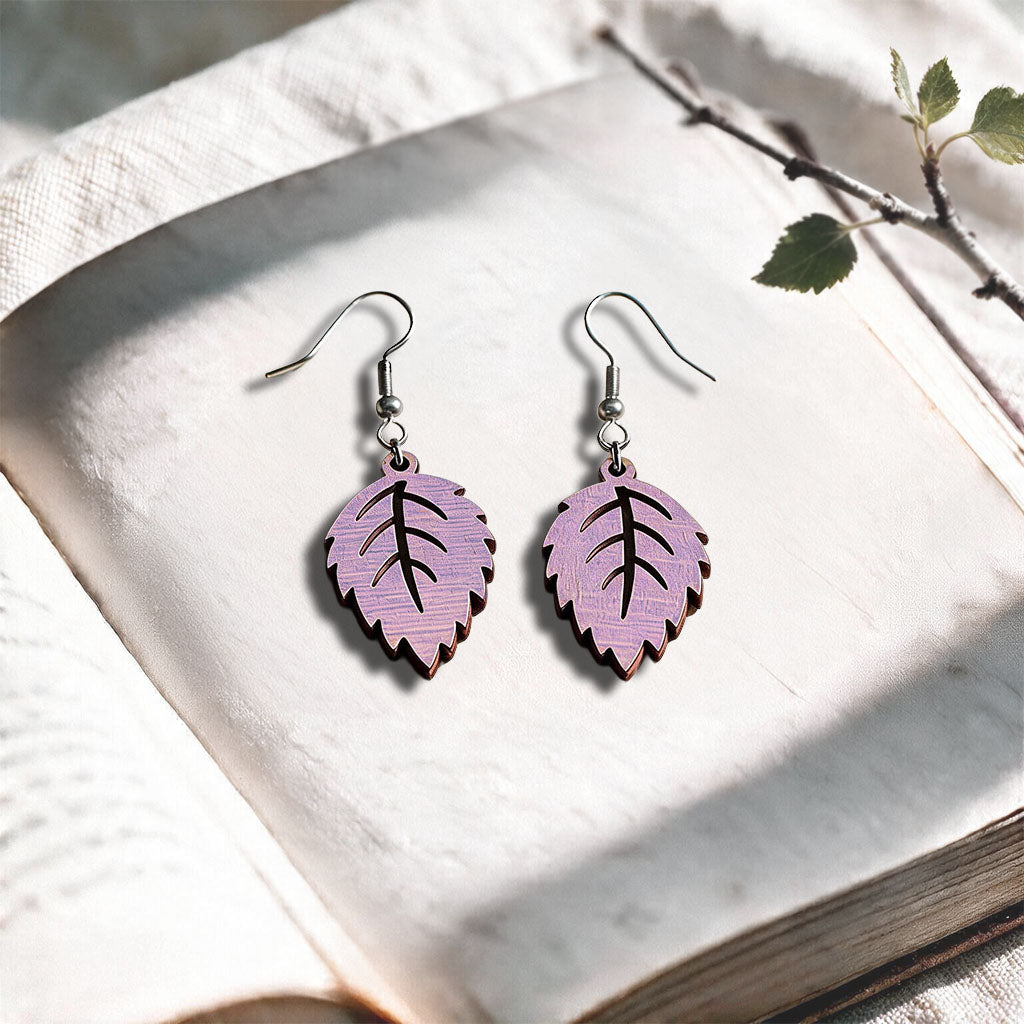 Smoke Lavender Mini Birch plywood earrings made in Finland, photographed on a vintage book in natural sunlight