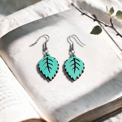 Turquoise Mini Birch plywood earrings made in Finland, photographed on a vintage book in natural sunlight