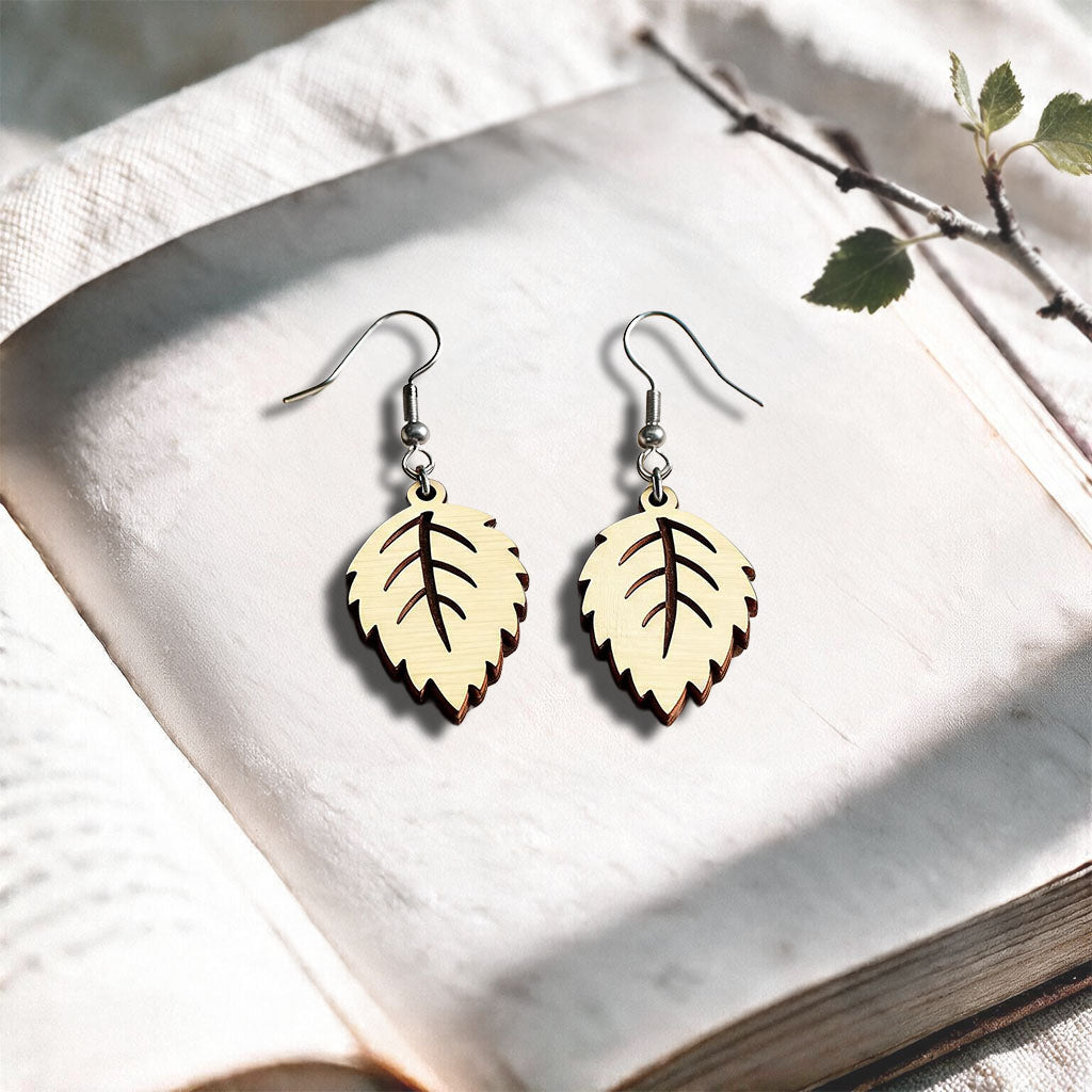 Vanilla Mini Birch plywood earrings made in Finland, photographed on a vintage book in natural sunlight
