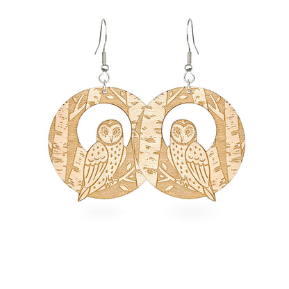 Handmade wooden owl earrings with detailed forest engraving, featuring owls resting among birch trees. Lightweight Nordic statement earrings crafted from Finnish birch plywood.